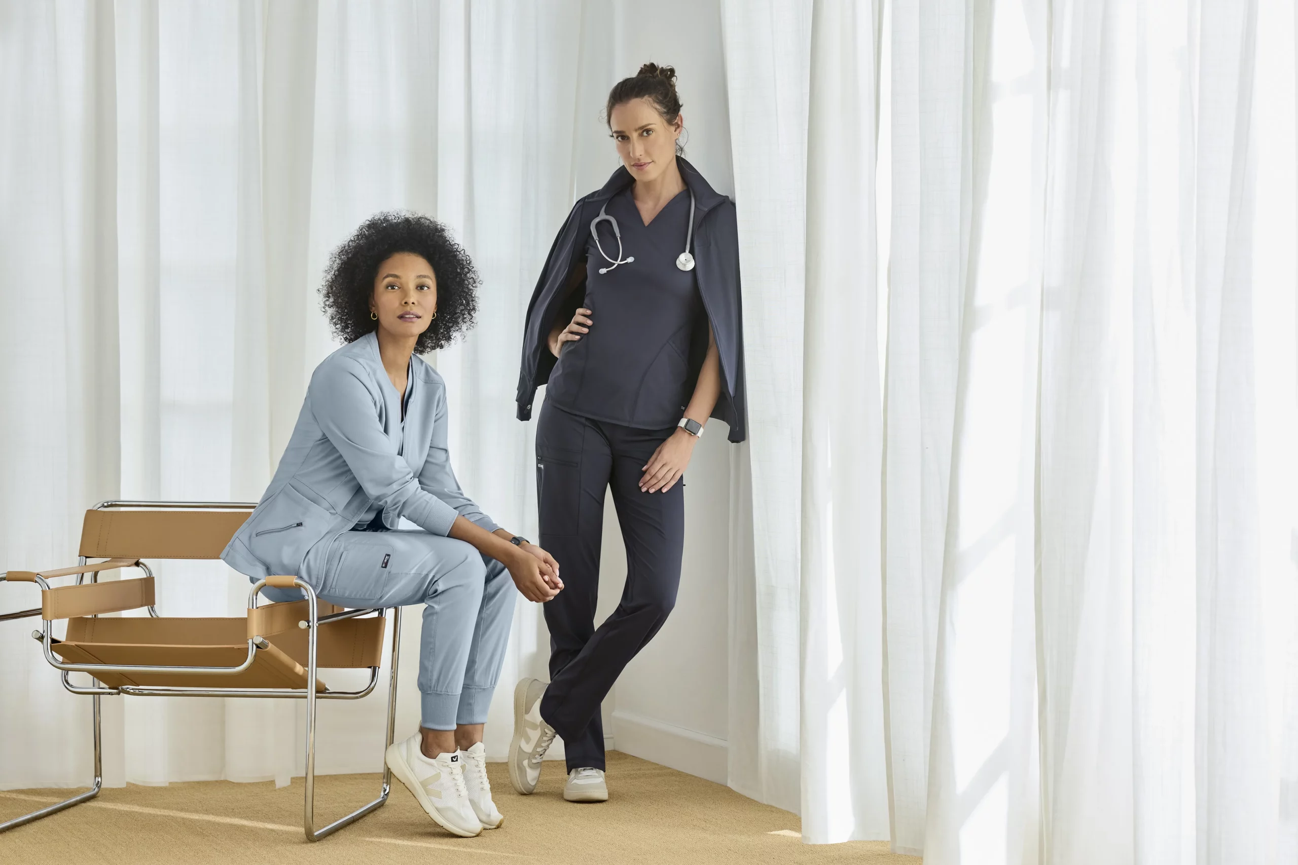 Two women wearing blue medical scrubs